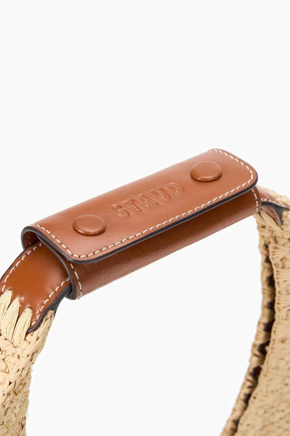 Close-up of a woven bag handle with a brown leather strap 