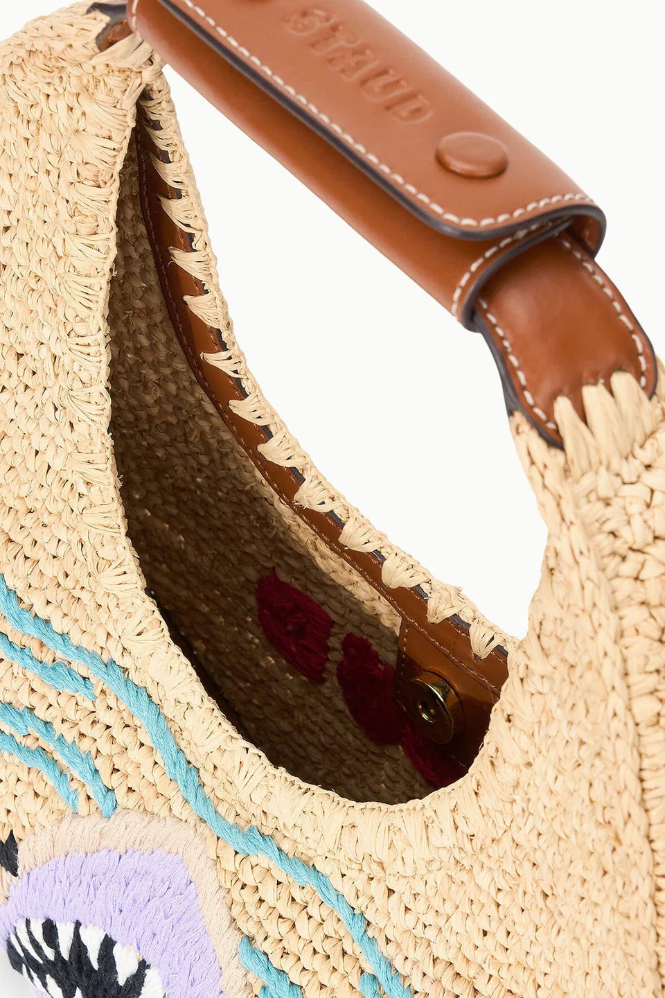 Close-up of a straw handbag with a brown leather handle on a white background