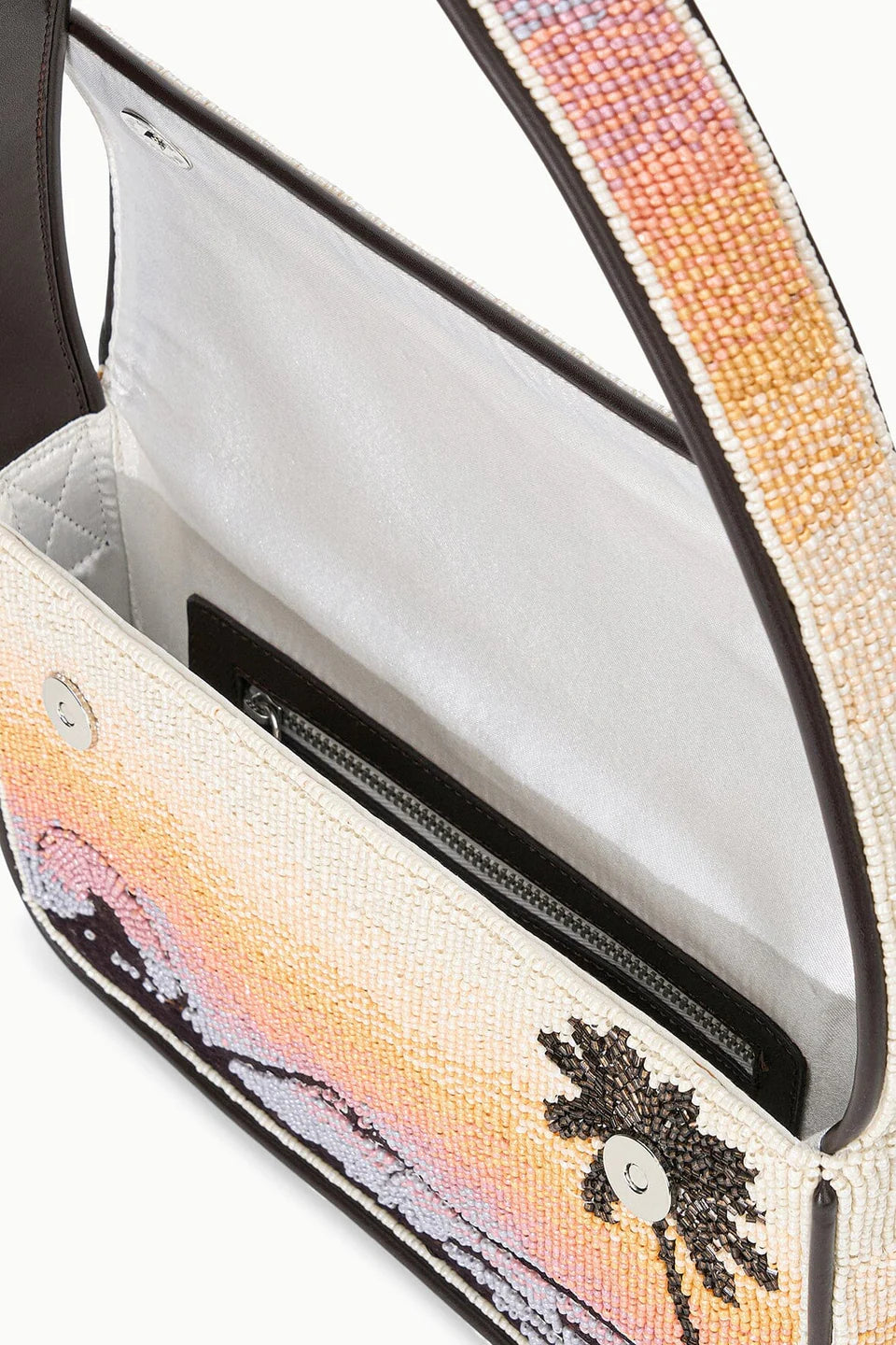 Close-up of a handbag with a palm tree design and beaded strap.