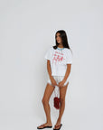 model wearing sea la ie graphic tee with a turquoise necklace on a white background