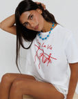 model wearing sea la ie graphic tee with a turquoise necklace on a white background