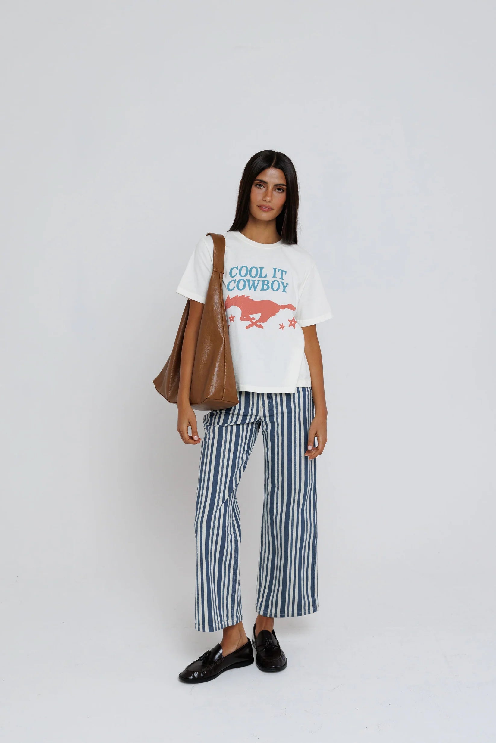 model wearing cool it cowboy tee with stripe pants on a white background
