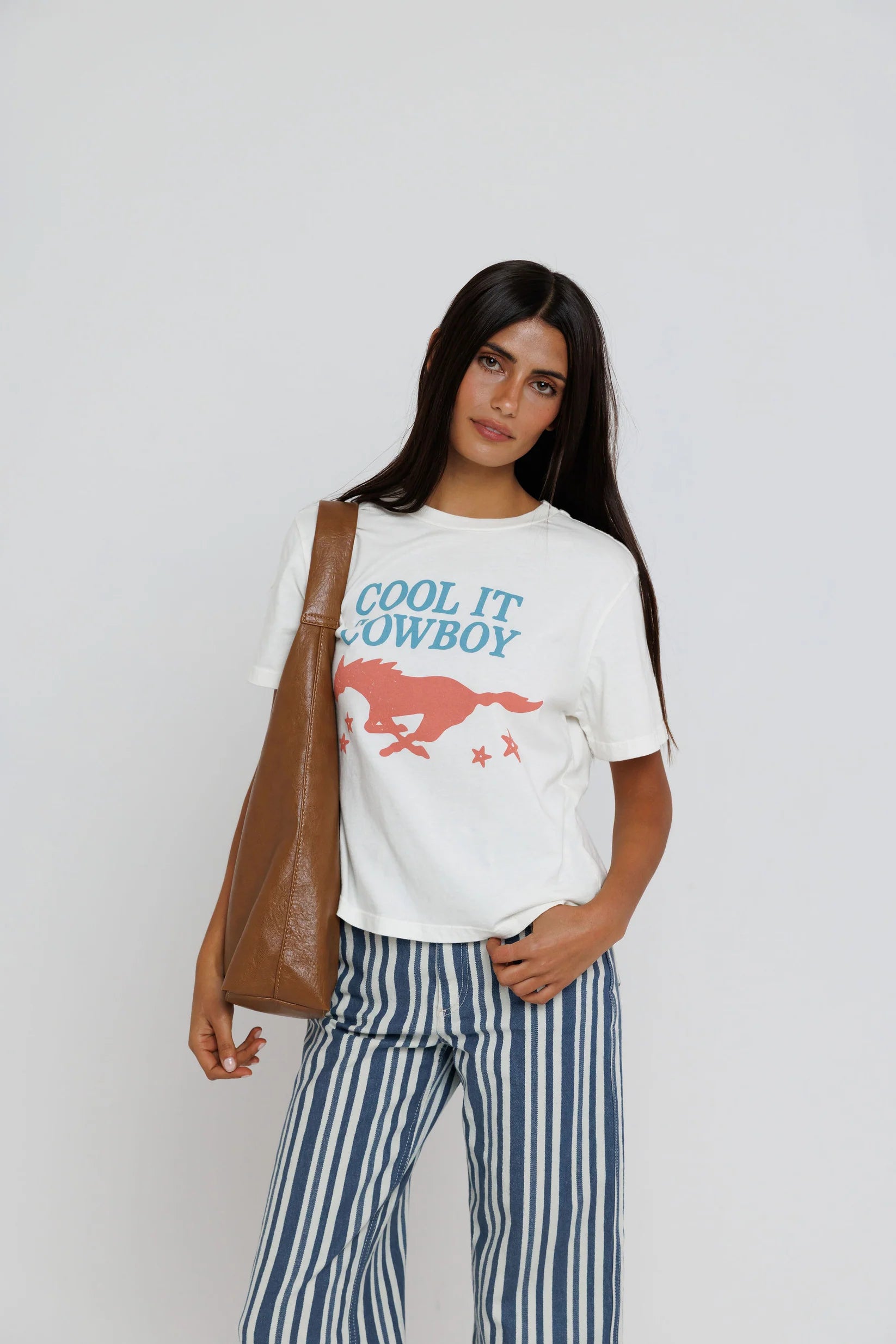 model wearing cool it cowboy tee with stripe pants on a white background