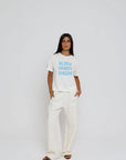 model wearing aloha howdy cheers short sleeve tee with white pants on a white background