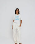 model wearing aloha howdy cheers short sleeve tee with white pants on a white background