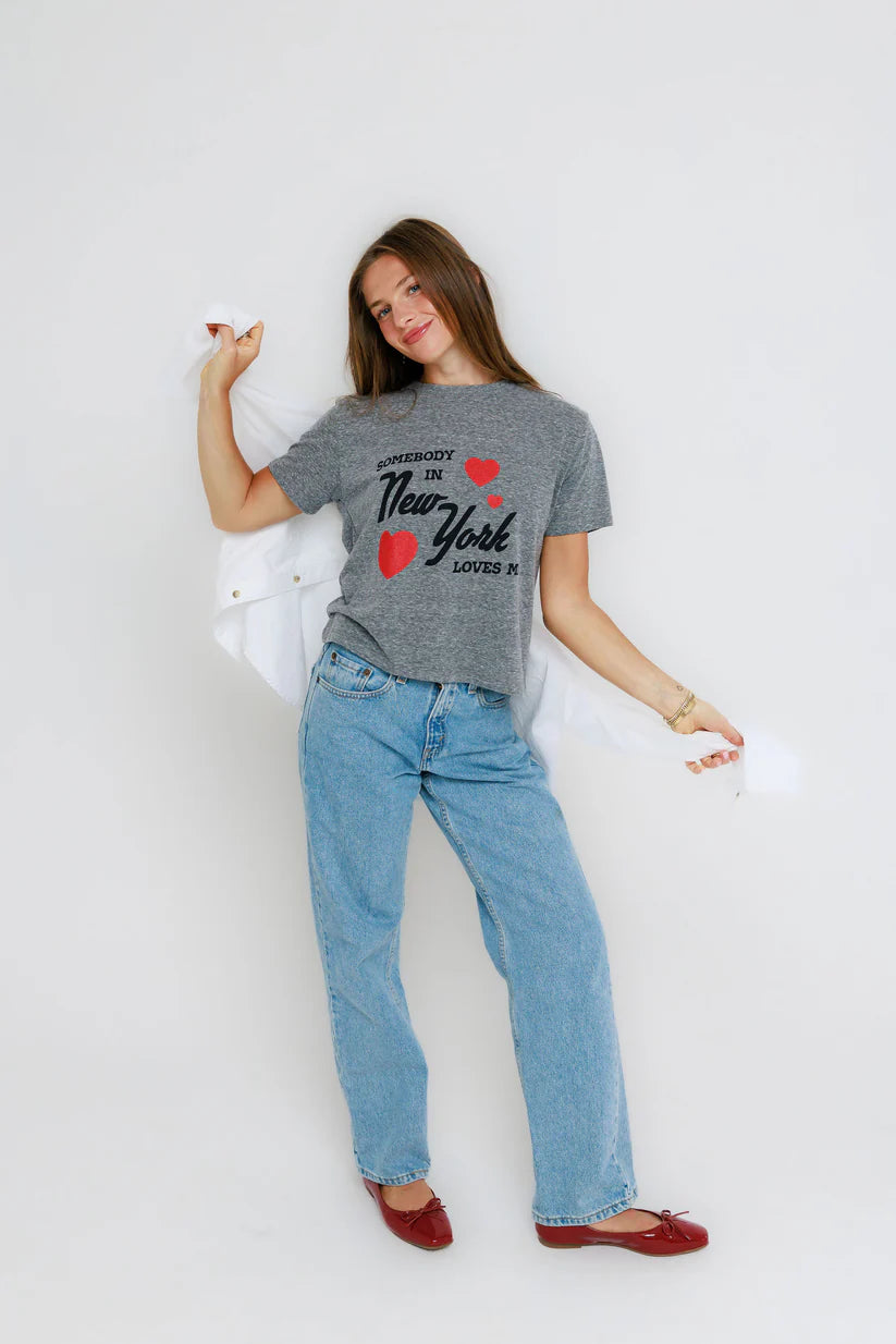 Person wearing a gray t-shirt with text and red hearts, blue jeans, and red shoes on a white background, full body view