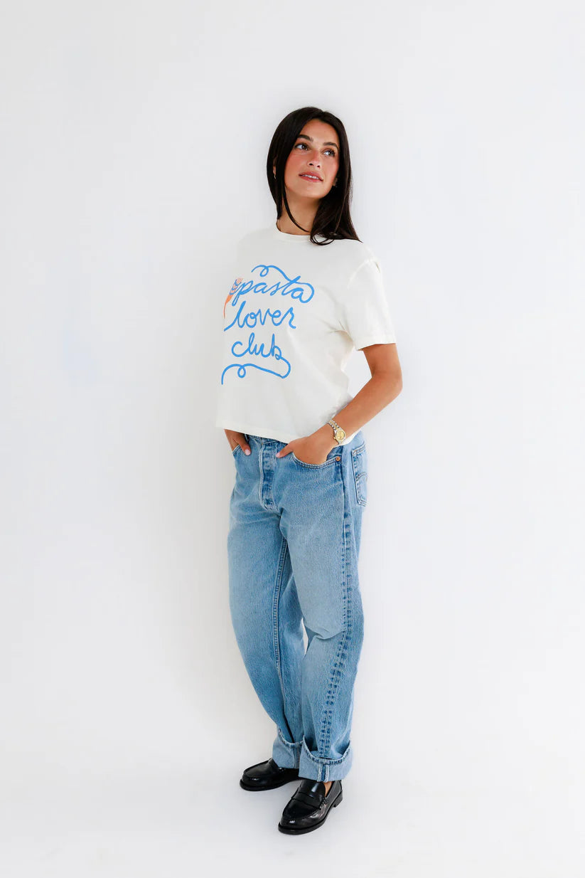 Person wearing a white t-shirt with blue text and light blue jeans on a white background, side