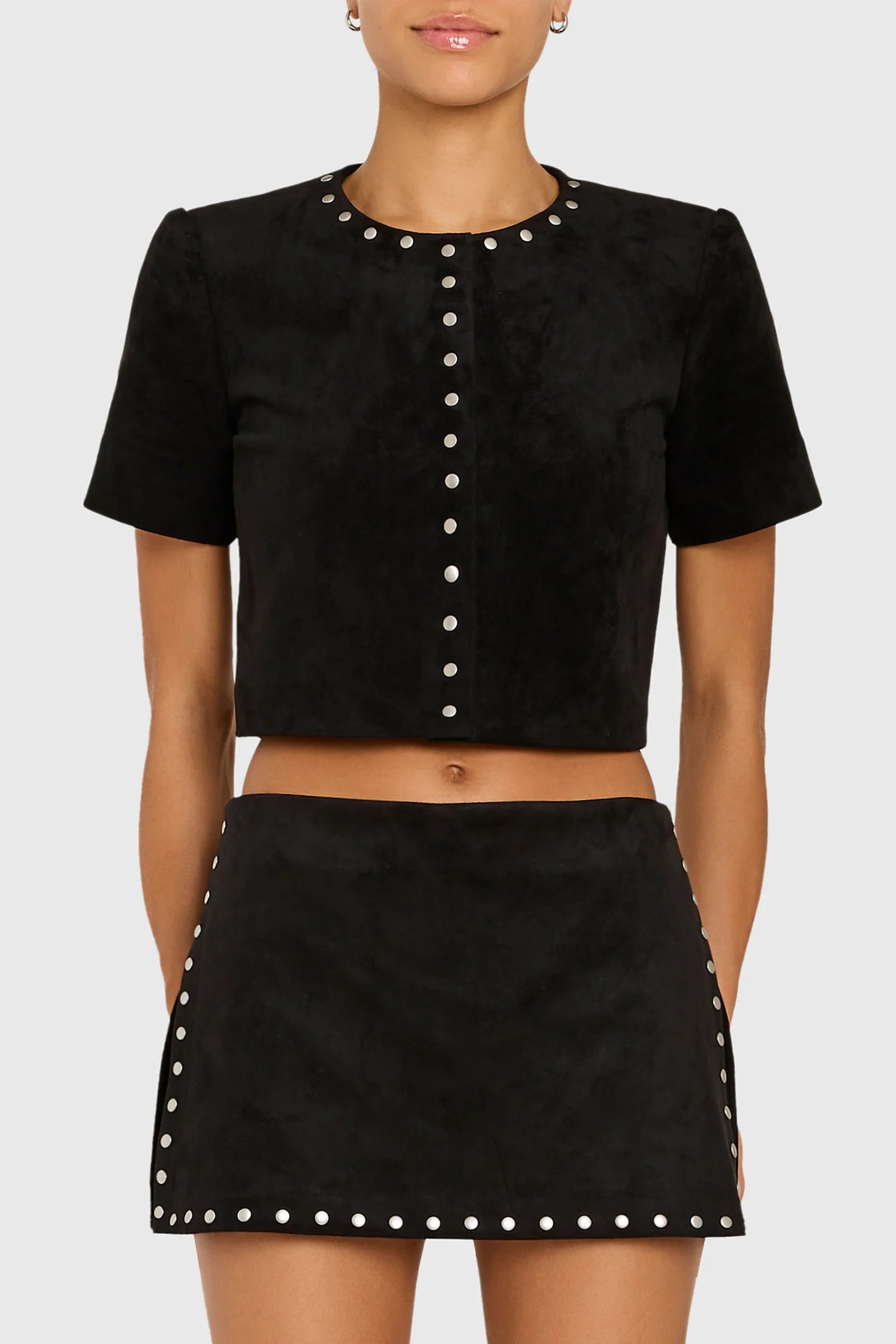 Model wearing studded black shirt and skirt on white back ground