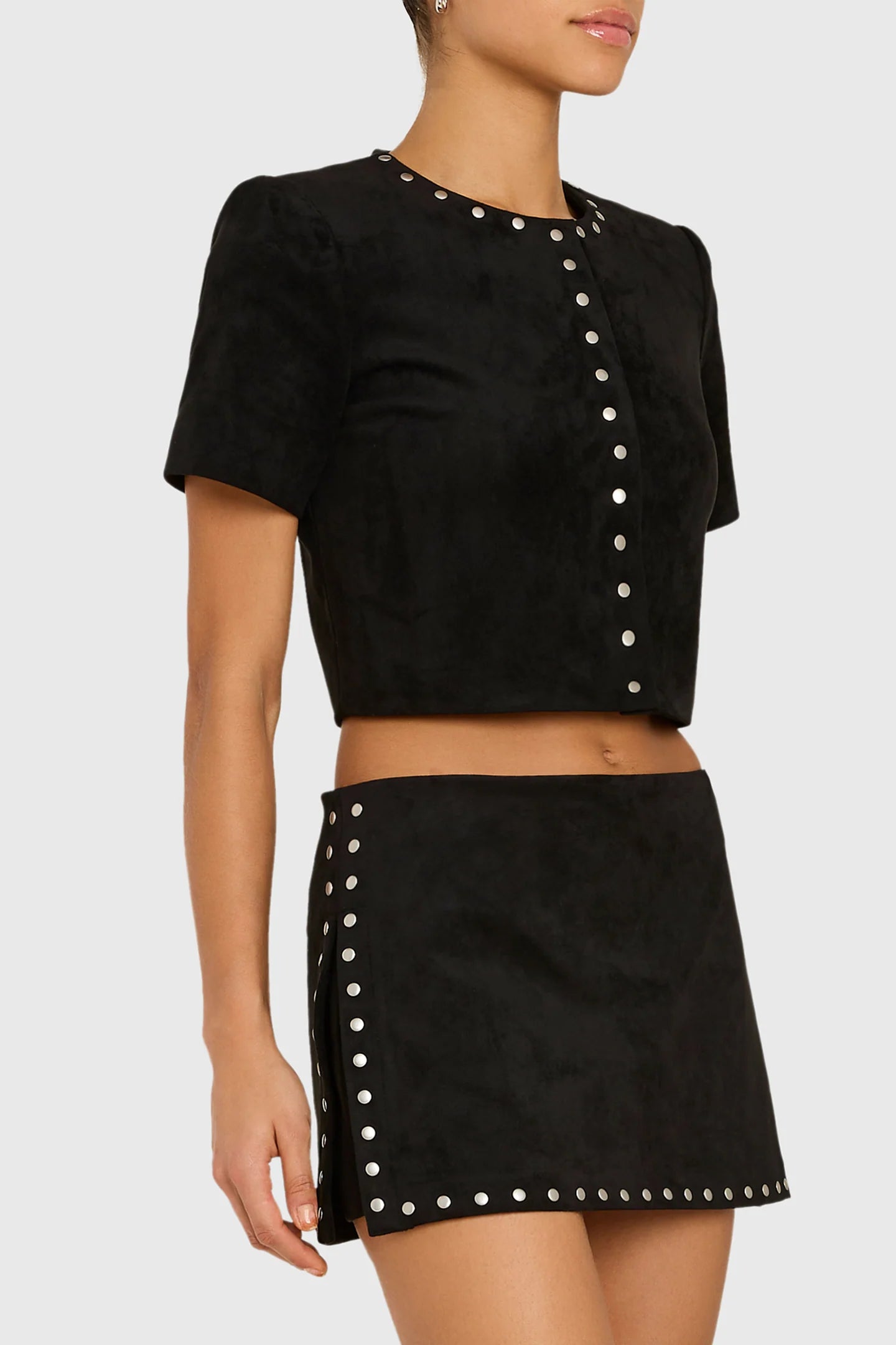 Model wearing studded black shirt and skirt on white back ground