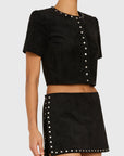 Model wearing studded black shirt and skirt on white back ground