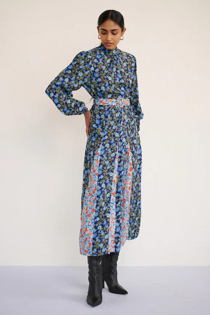 Woman wearing a long floral dress with a belt on a white background