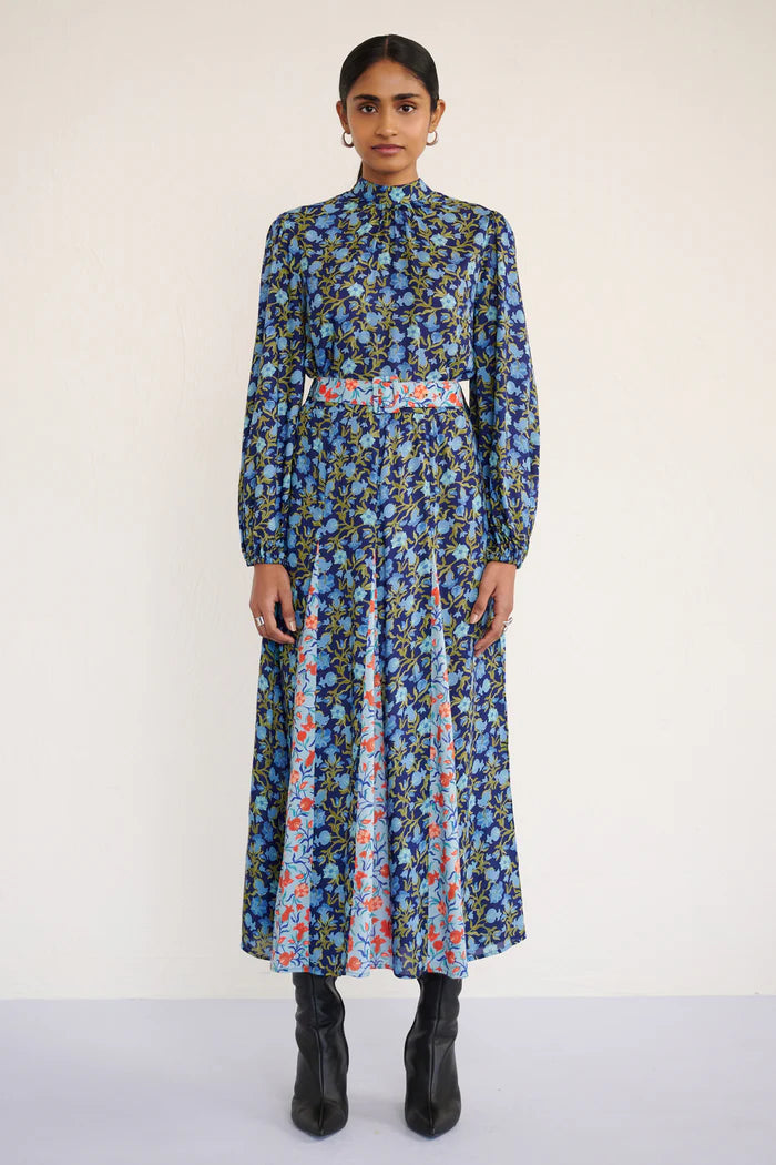 Woman wearing a long floral dress with a belt on a white background, front