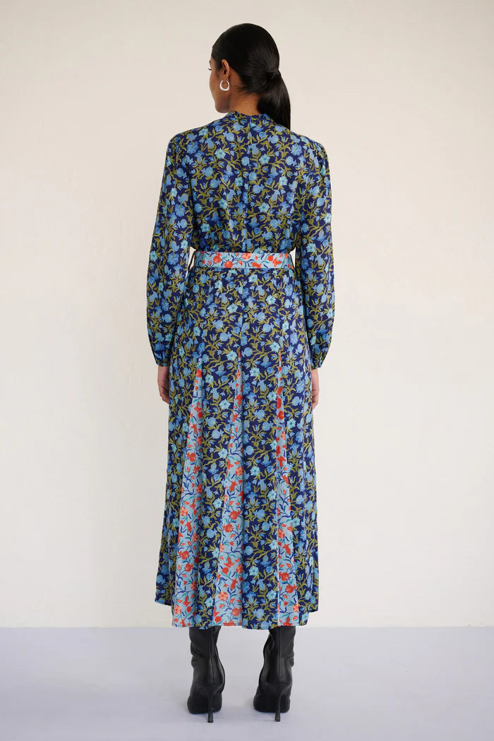 Woman wearing a blue floral dress with a belt against a white background, back