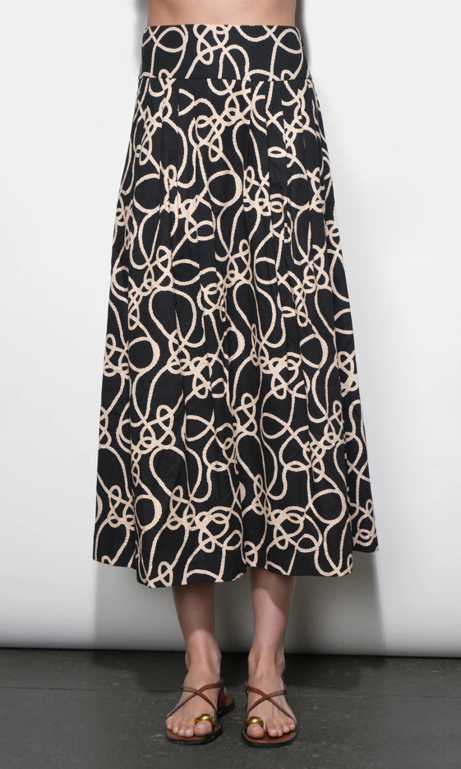 Person wearing a black and beige patterned skirt against a white background