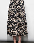 Person wearing a black and beige patterned skirt against a white background