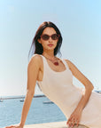 Solange Sunglasses Scarlet Chroma + Bordeaux on model with average, square face shape, sitting on a ledge by the sea