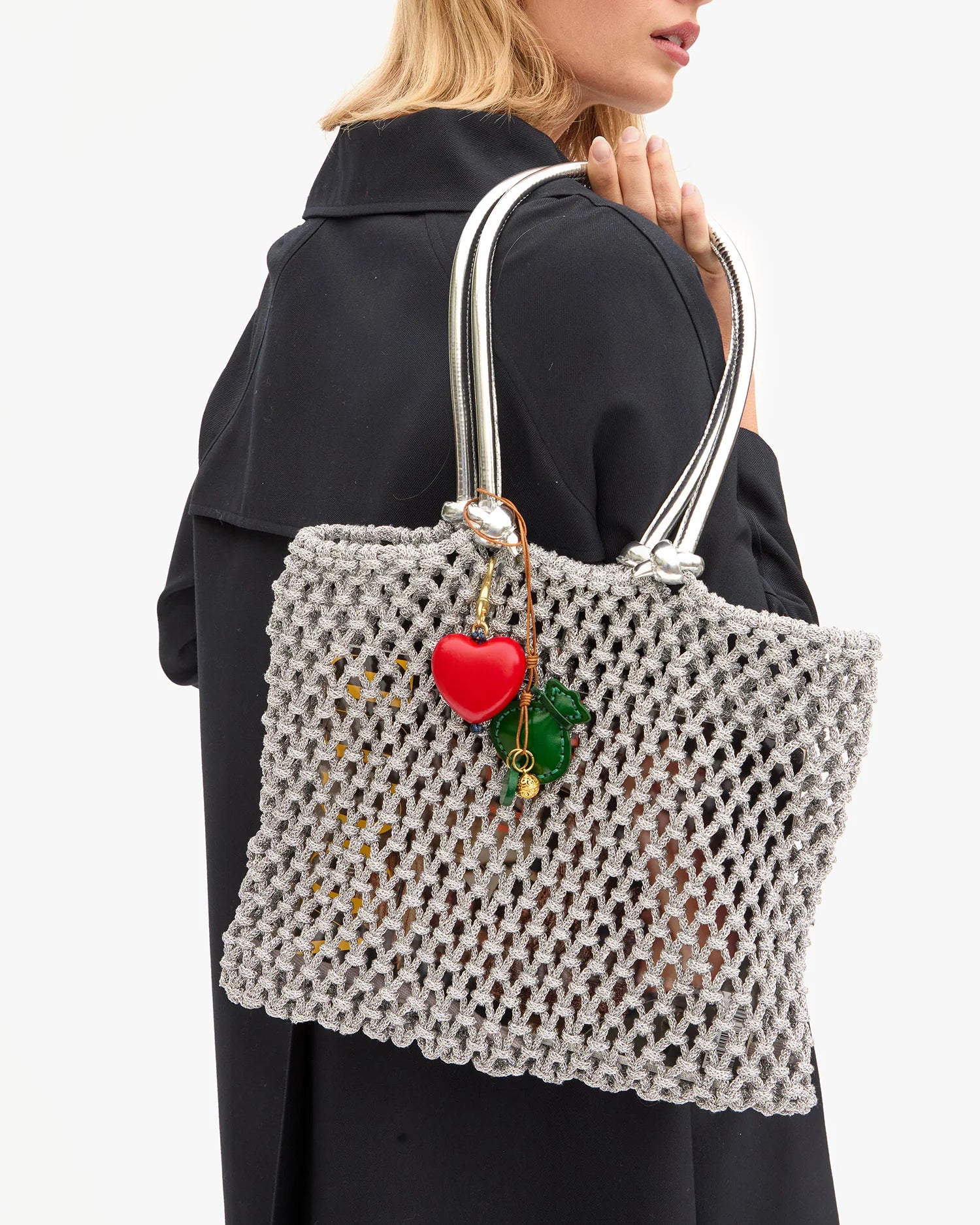 Person holding a textured handbag with a heart charm on a white background