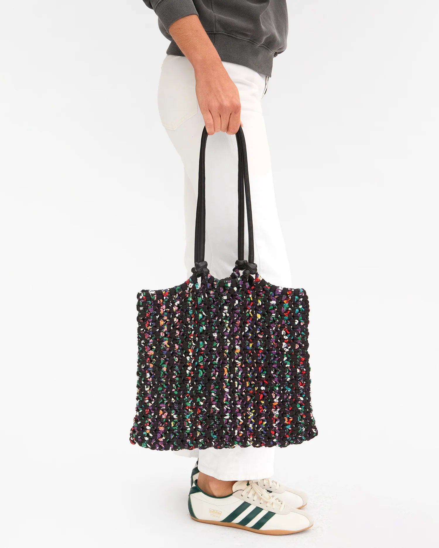 Person holding a multicolored tote bag against a white background