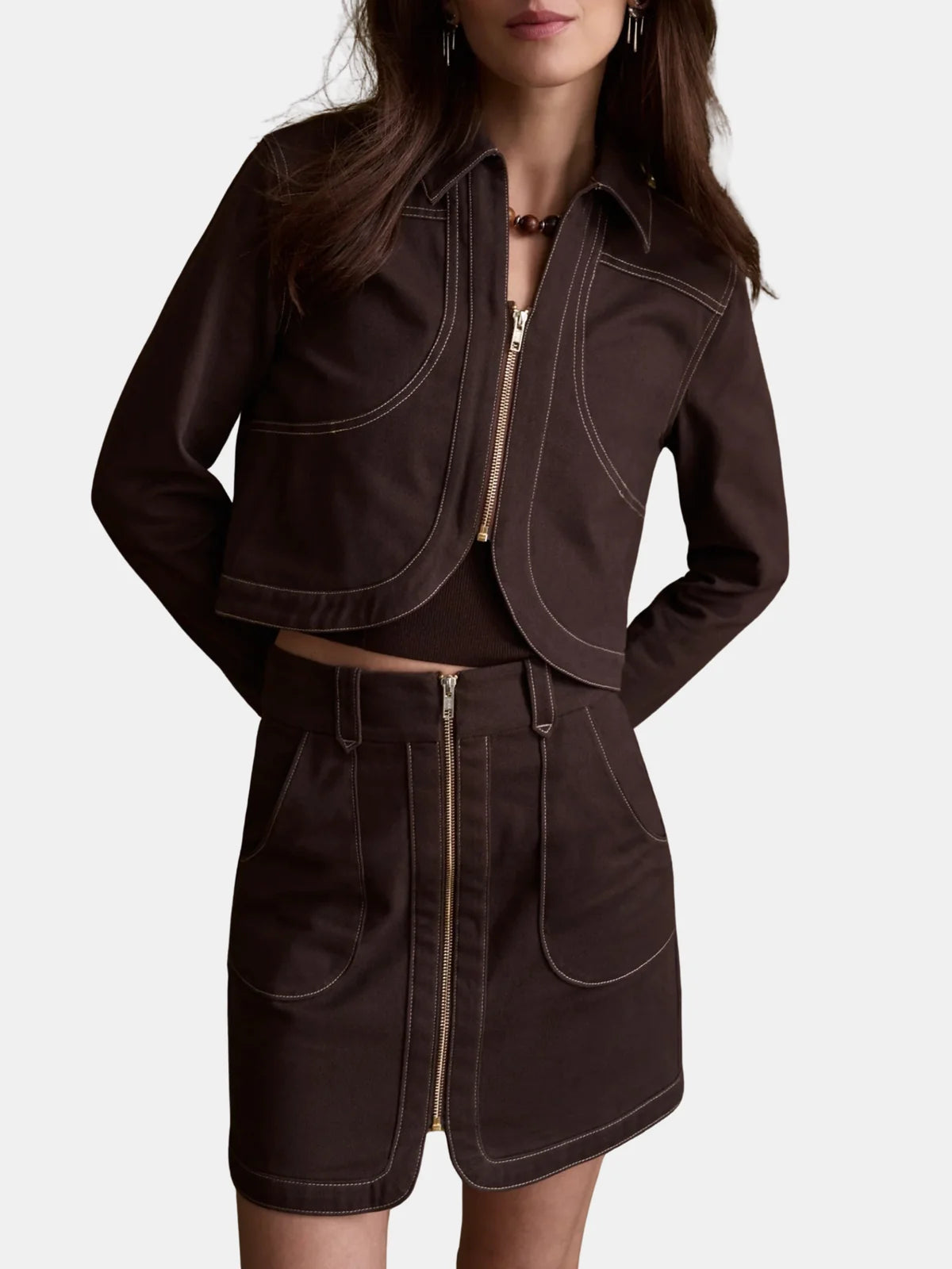 model wearing a chocolate jacket with matching mini skirt with gold zipper on a white background