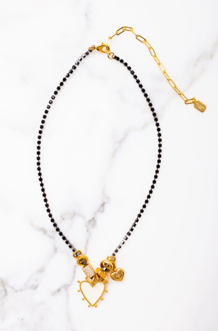 Necklace with black beads and gold accents on a white marble background