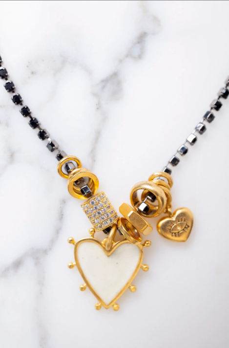 Necklace with gold heart pendant and black beads on a marble background
