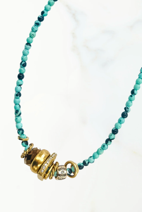 Necklace with turquoise beads and gold charms on a white background