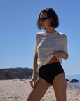 The Linen Perfect Tee In Cream with black swim bottoms