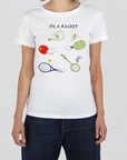 A woman wearing a white short-sleeve t-shirt with a colorful tennis-themed graphic that reads 'ITS A RACKET' above illustrated rackets and tennis balls, paired with dark blue jeans against a light gray background.