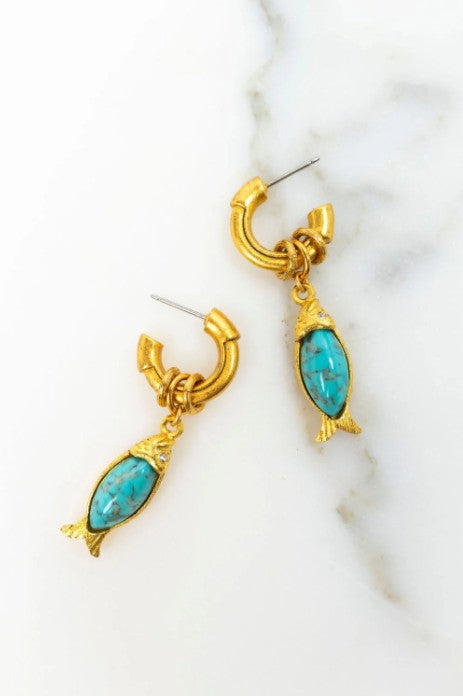 Gold earrings with turquoise stones on a marble surface