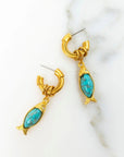 Gold earrings with turquoise stones on a marble surface