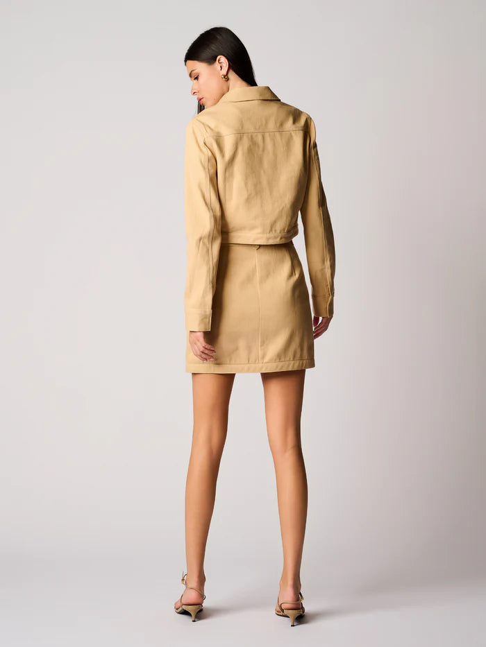 Woman wearing a beige jacket and skirt set on a plain background