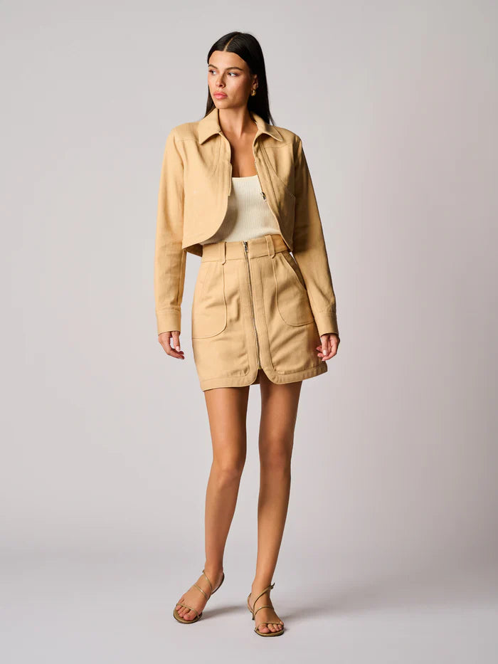 Woman wearing a beige jacket and skirt set on a plain background