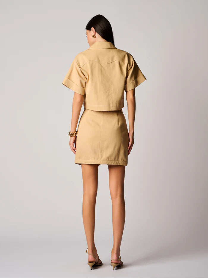 Woman wearing a beige outfit against a plain background