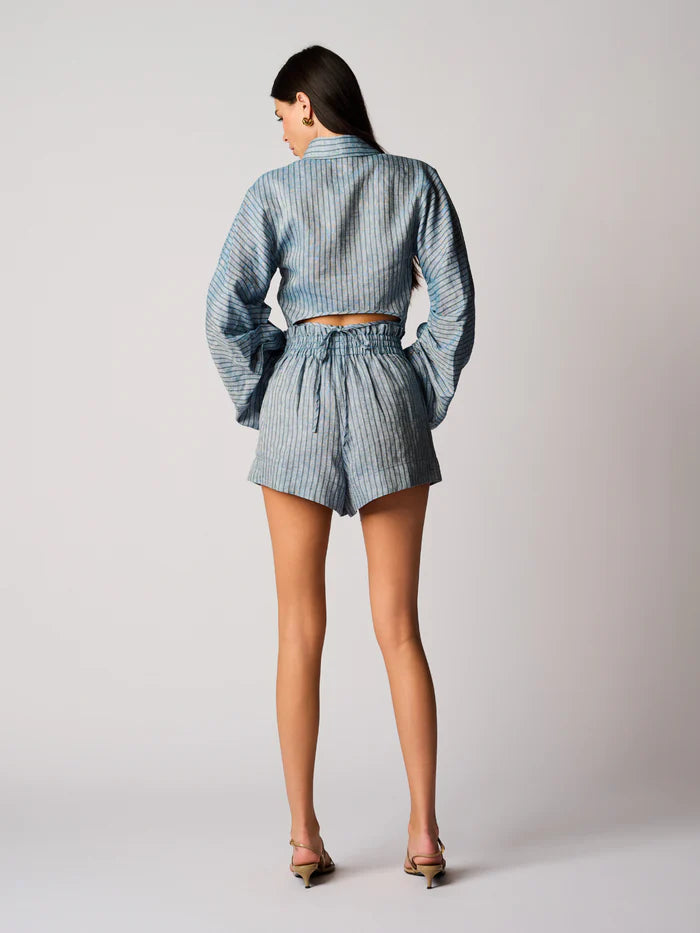 Person wearing a blue checkered outfit with a jacket and shorts on a plain background, back