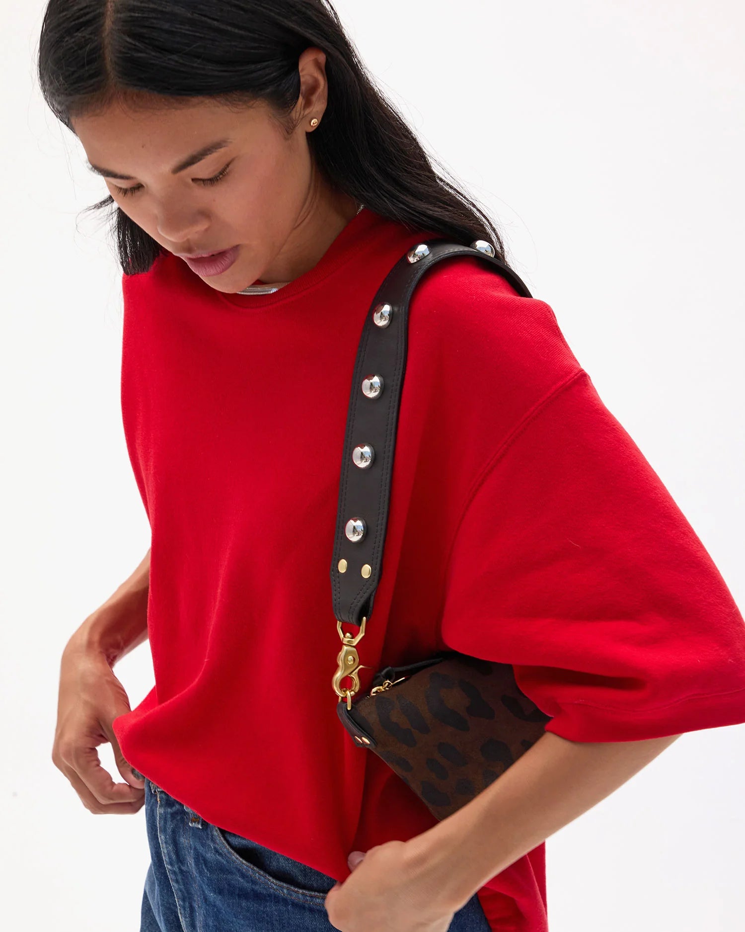 Person wearing a red sweater with a black and gold handbag on a white background