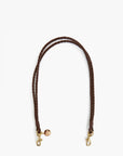 A dark brown braided leather strap with gold-tone metal hardware, including two snap hooks and a small round charm, displayed on a clean white background.