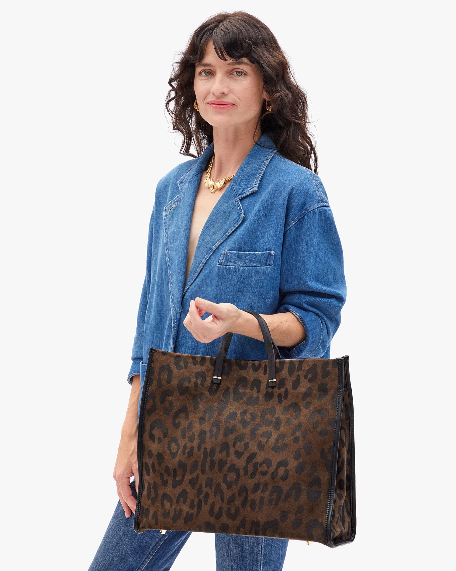 Woman holding a leopard print handbag against a white background