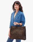 Woman holding a leopard print handbag against a white background