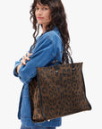 Woman carrying a leopard print tote bag on a white background