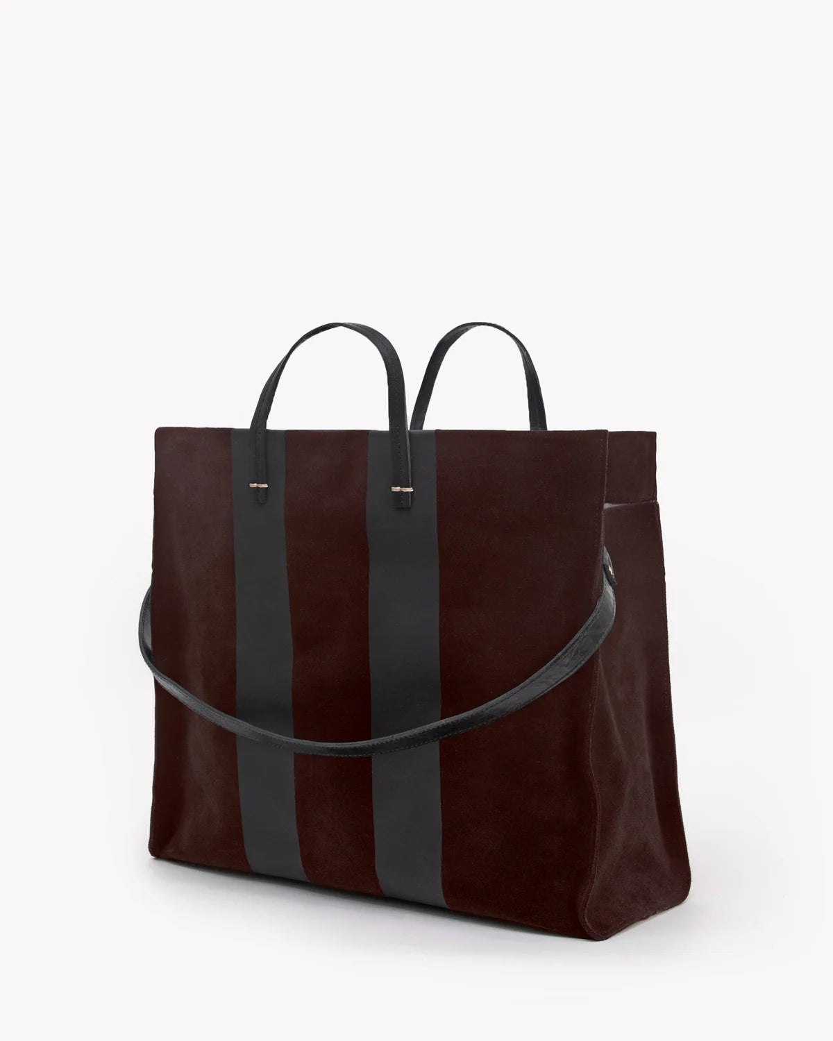 A dark brown suede tote bag with two vertical black leather stripes and black leather handles, shown on a clean white background.