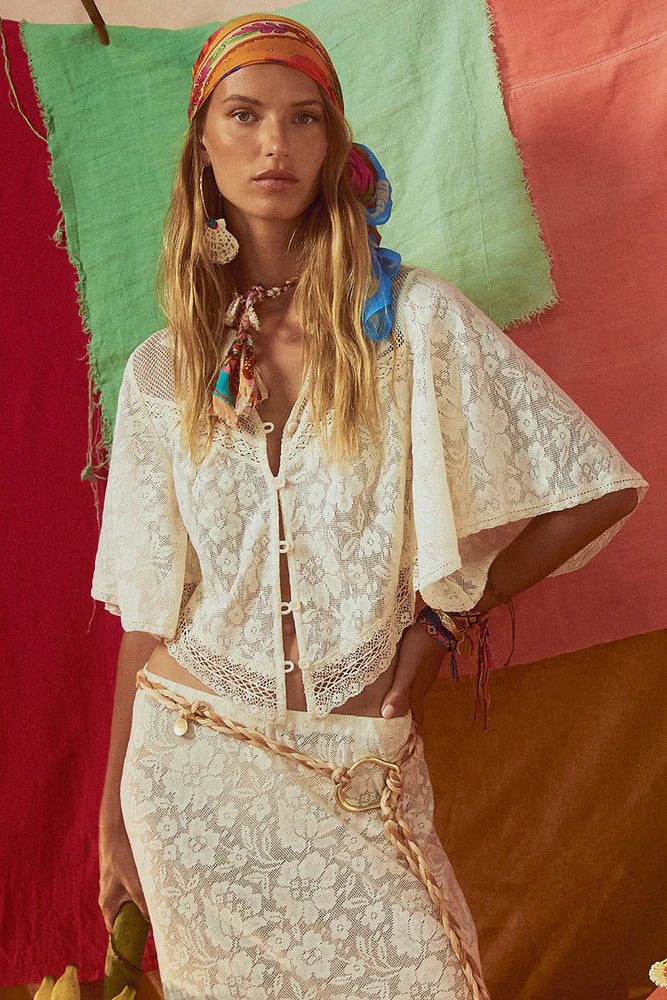 Woman wearing a white lace outfit with colorful accessories against a multicolored background