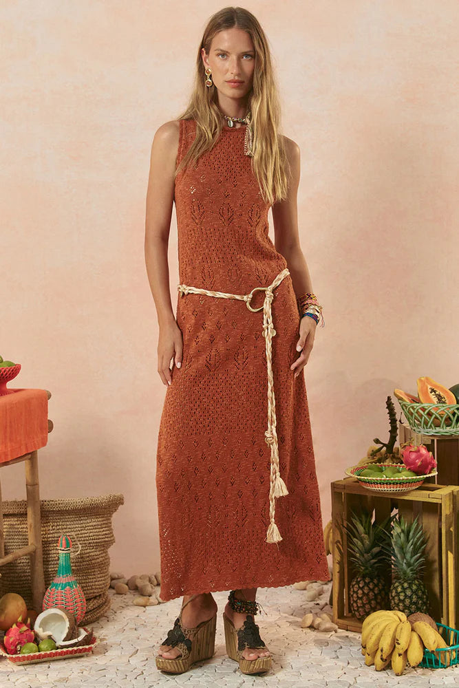 Woman wearing a rust-colored dress with tassels in a rustic setting