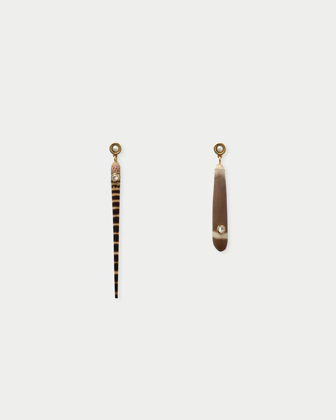 Pair of long, thin earrings with decorative elements on a light gray background