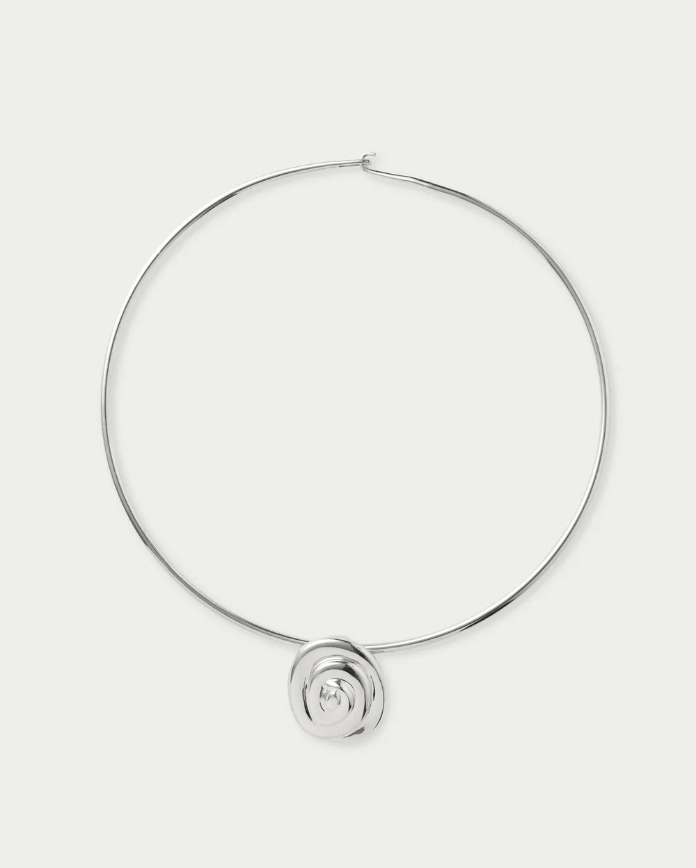 A minimalist silver-toned wire hoop necklace with a small circular spiral pendant at the bottom center, displayed on a clean light gray background.