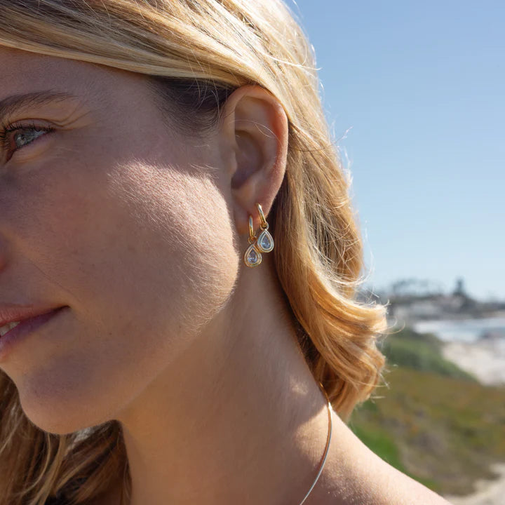 Close-up of a woman wearing gold earrings with a blurred background