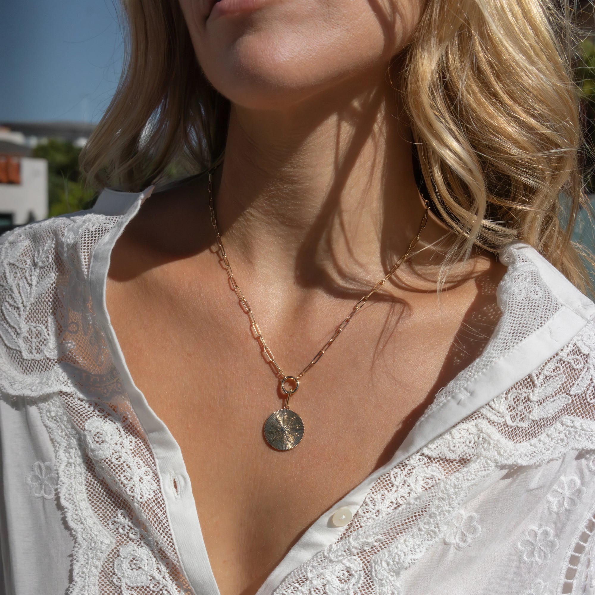 Finn Paperclip Charm Necklace with coin-like charm attached to it