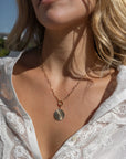 Finn Paperclip Charm Necklace with coin-like charm attached to it