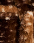 Close-up of a brown faux fur or animal-print textile with dark brown and tan sections and irregular cream spots.