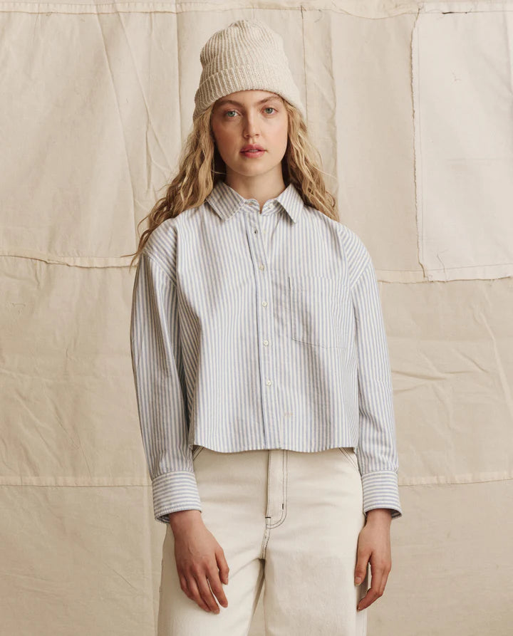 Woman wearing a striped shirt and beige beanie against a beige background