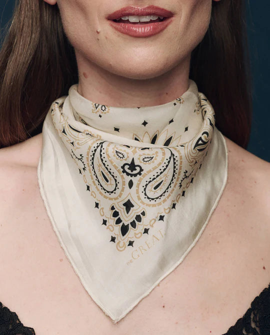Woman wearing a beige bandana with black paisley pattern
